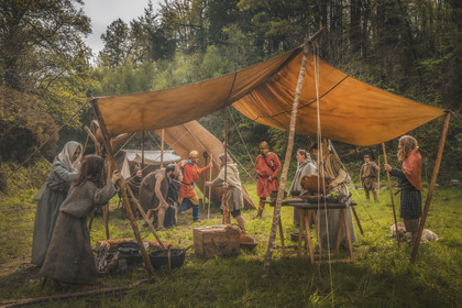 Le système fiscal des charges ruine les faibles, l’impôt doit être rentable, les puissants exproprient, asservissent, maltraitent, la corruption règne. Nombreux sont les petits propriétaires, les pauvres libres, les soldats déserteurs, les esclaves à fuir vers les maquis ou les forêts. La situation de crise encourage les bagaudes à sortir de leurs maquis pour élargir le territoire libéré, et surtout pour piller la partie civilisée, utile des Provinces : attaquer les villae, cerner et prendre des vici, ces grosses bourgades, et même encercler les villes. Sans parler, naturellement, de l'accroissement de l'emprise de ces bandes sur les grands chemins. Les bagaudes recrutent parmi la plèbe et les esclaves. Une première bagaude a lieu en 445 qui devait être réprimée par les Alains de Goar (chef Alain dont la mission confiée par Aetius était de surveiller les armoricains) lorsque Germain d’Auxerre intervient à Ravenne en faveur des armoricains. Une trêve est annoncée et l’Armorique est pacifiée. Cependant, une nouvelle révolte armoricaine éclate, menée par Tibatto, rompant la parole donnée à l’évêque d’Auxerre. La population servile rejoint la bagaudie. La répression est sans pitié.Site - Pont-de-BuisFigurants et campement - Letavia